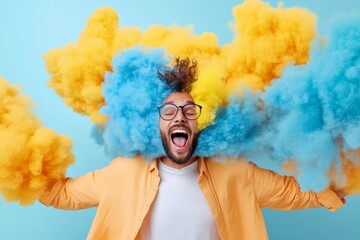 Man is covered in smoke and is laughing. The smoke is yellow and blue. The man is wearing glasses and a yellow shirt