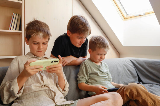 Siblings - family fun on the sofa with technology