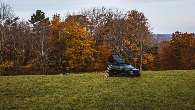 Truck with roof top tent and ladder in a field in Maine in the fall.
