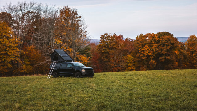 Pickup truck with tent and ladder at campsite in Maine in the fall.