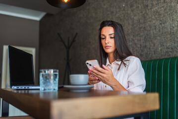 Fototapeta premium Focused businesswoman using smartphone in cafe