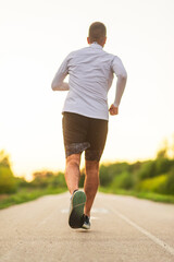 Athlete running on a road at sunset pursuing goals