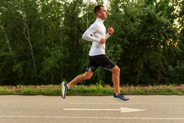 Young man running in park wearing wireless earbuds