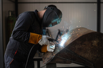 Industrial worker using welding tool on metal in factory