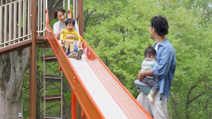 公園の遊具で遊ぶ四人家族