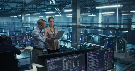 Diverse Team of Engineers Collaborating in a High-tech Data Center, Analyzing Server Performance on a Laptop Computer. Specialists Reviewing System Logs to Ensure Minimal Downtime Across the Network - Powered by Adobe