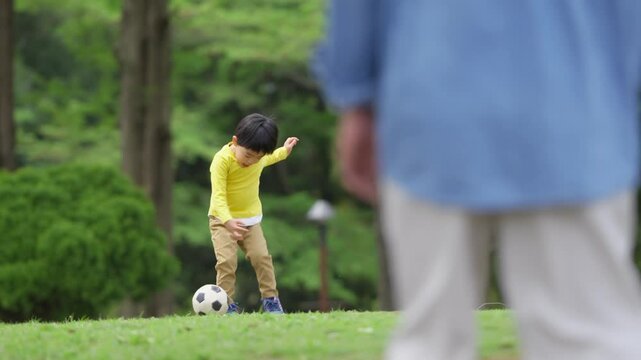 公園で父親とサッカーをする4歳の男の子