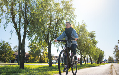 Woman riding a bicycle outside the city center, enjoying a rejuvenating escape from urban life to...