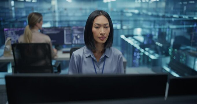 Portrait of a Dedicated Data Analyst in a Data Center Office, an Asian Woman Concentrates on Her Work on a Computer, Managing System Security and Processing Key Information Online