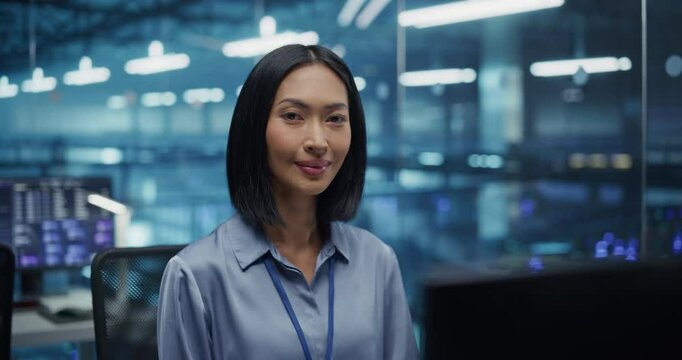 Portrait of a Data Center Administrator Working Behind a Desk, Optimizing Server Configurations on a Desktop Computer. Beautiful Female Specialists Looking at Camera and Smiling. Arc Footage
