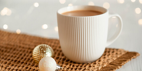A white cup with hot coffee or tea on a white wooden table.