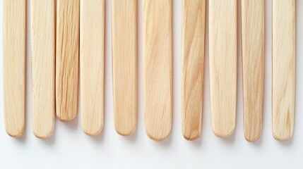 68.A detailed shot of wooden ice cream sticks, evenly aligned and isolated against a white backdrop. The sticks have a smooth, polished finish, showcasing their natural wooden texture and suitability