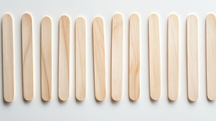 68.A detailed shot of wooden ice cream sticks, evenly aligned and isolated against a white backdrop. The sticks have a smooth, polished finish, showcasing their natural wooden texture and suitability