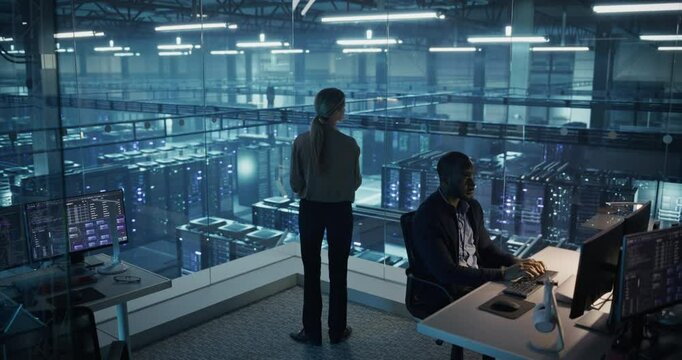 Female Information Technology Engineer Reviews Security Logs on Her Tablet Computer in a High-Tech Data Center, Analyzing Potential Risks to Ensure Network&rsquo;s Safety and Compute Power