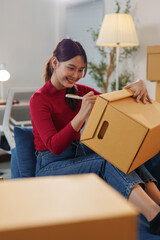 Startup girl, SME business owner, working with parcel boxes Recording names Address on the packaging box at the home office for delivery to the customer. Online sales ecommerce concept.