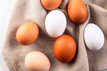 Chicken eggs on linen napkin on white background.