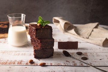 Chocolate brownies with melted chocolate topping, almond and leaves mint with glass of milk on...