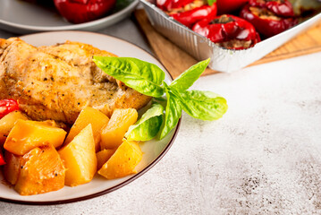 Plate with baked fillet with potatoes and stuffed peppers on table for lunch.  healthy food.