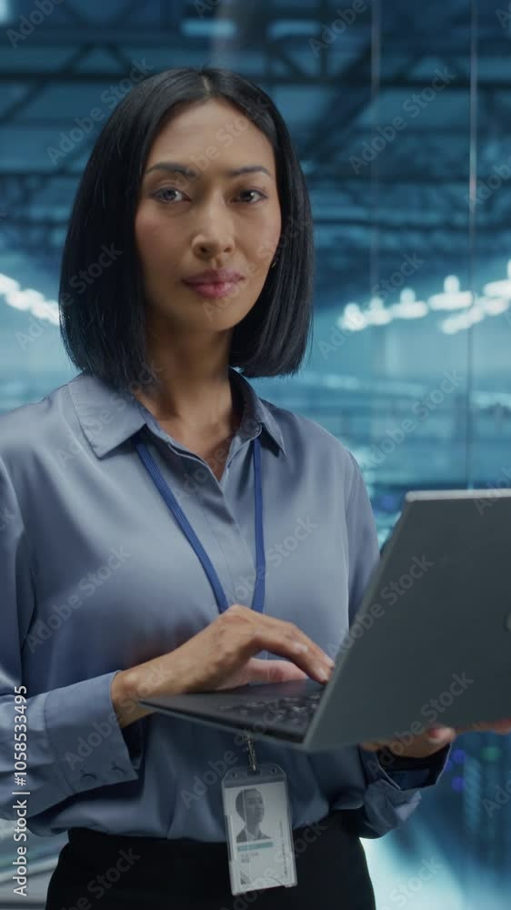 Poster Vertical Screen: Asian Female Data Center Specialist Analyzing System Performance on a Laptop, Optimizing Cybersecurity Protocols in a High-tech Facility. Developer Monitors Real-time Data on Computer