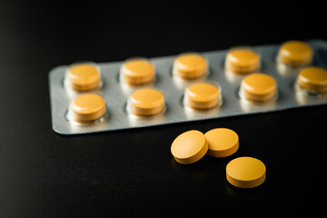 Antipyretic analgesic pills Medicine tablet Brown Yellow in blister pack on a black background