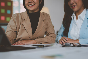 Two Asian businesswomen use laptops and smartphones in an open space office. Business concept. Data analysis, roadmap, marketing, accounting, auditing.