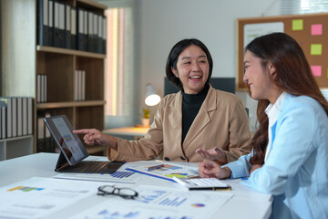 Two Asian businesswomen rejoicing over business success, smiling and expressing joy. Success in starting an online business partner teamwork concept.