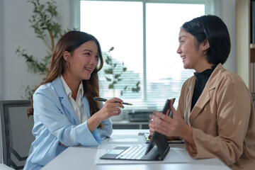 Two Asian businesswomen rejoicing over business success, smiling and expressing joy. Success in starting an online business partner teamwork concept.