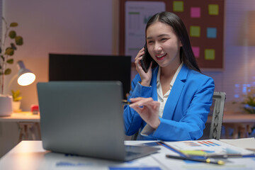 Asian businesswoman in a suit in the office is happy while using a smartphone to contact customers, online, video calls in business finance, marketing, taxes of the company.