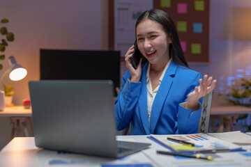 Asian businesswoman in a suit in the office is happy while using a smartphone to contact customers, online, video calls in business finance, marketing, taxes of the company.