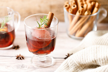 Glass of mulled wine with slices of orange and cinnamon sticks.