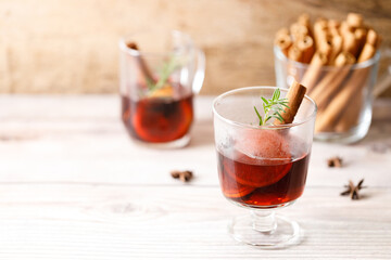 Glass of mulled wine with slices of orange and cinnamon sticks.