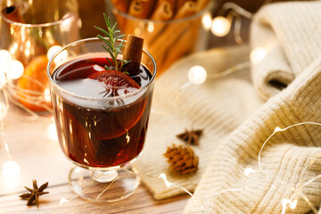 Glass of mulled wine with slices of orange and cinnamon sticks.