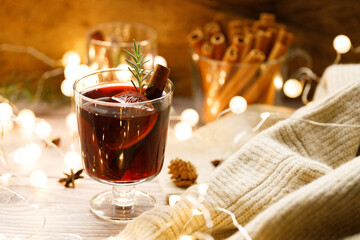 Glass of mulled wine with slices of orange and cinnamon sticks.
