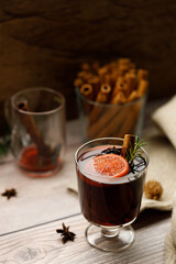 Glass of mulled wine with slices of orange and cinnamon sticks.