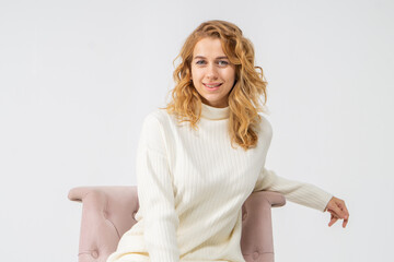 Attractive young blonde girl sits in a pink chair, white background, copy space