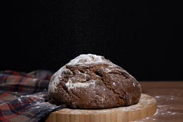 Dark bread on wooden table with black background