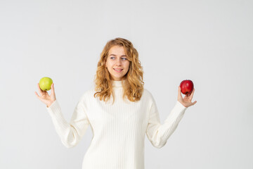 Happy attractive blonde young girl holding red and green apples, white background, copyspace. Concept of choice