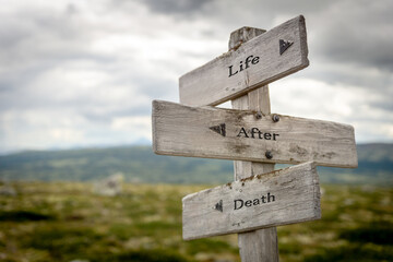 life after death text quote written on wooden signpost oudoors in mountain scenery.