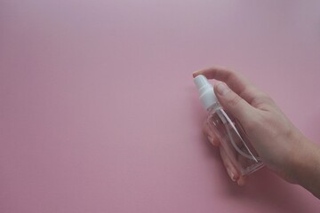 Woman hands holding cosmetic bottle on pastel pink background. Blank plastic package container mock up with place for text. woman hand hold a blank cosmetic container