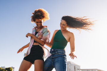 Energetic young friends dancing and laughing outdoors