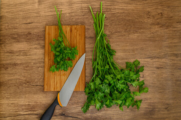 Świeże zioła, natka pietruszki pęczek na desce do krojenia i nóż, kuchenna tapeta © Paweł Kacperek