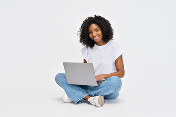 Happy young African American girl college student sitting isolated at white background using laptop...