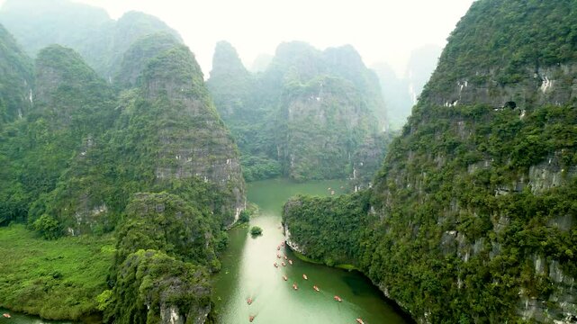 Aerial View Of Tourists On Boat Exploring Trang An By The River Along Limestone Rock Formations In Ninh Binh, Vietnam.
