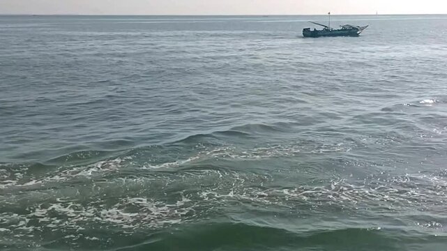 
Fishing boats traverse the calm sea. 
