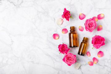 Rose essential oil on a textured background.Roses and a bottle of rose perfumed water.Aromatherapy treatment. Beauty concept. Spa procedure.Natural organic oil.Anti-stress,detox relax.Place for text