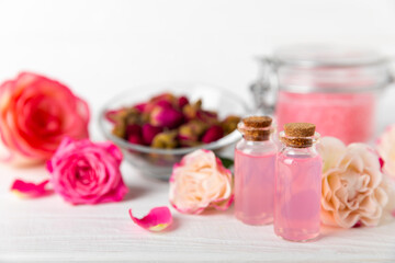 Rose essential oil on a textured background.Roses and a bottle of rose perfumed water.Aromatherapy treatment. Beauty concept. Spa procedure.Natural organic oil.Anti-stress,detox relax.Place for text