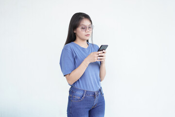 beautiful Asian woman with a serious expression exchanges messages on her smartphone against a white background