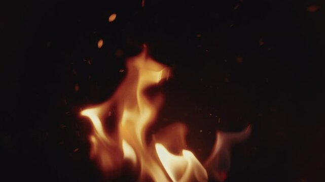 Slow motion Macro shot of wood logs burning in a campfire with sparks and smoke