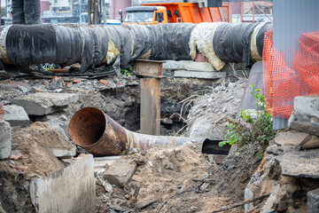 Scattered fragments of water, gas pipes in excavated trench. Worn infrastructure, pipe replacement...