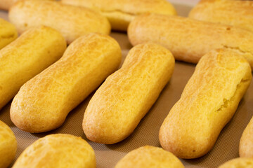 fresh eclairs on a baking sheet.Choux pastry.Dessert.Baking process.Food concept
